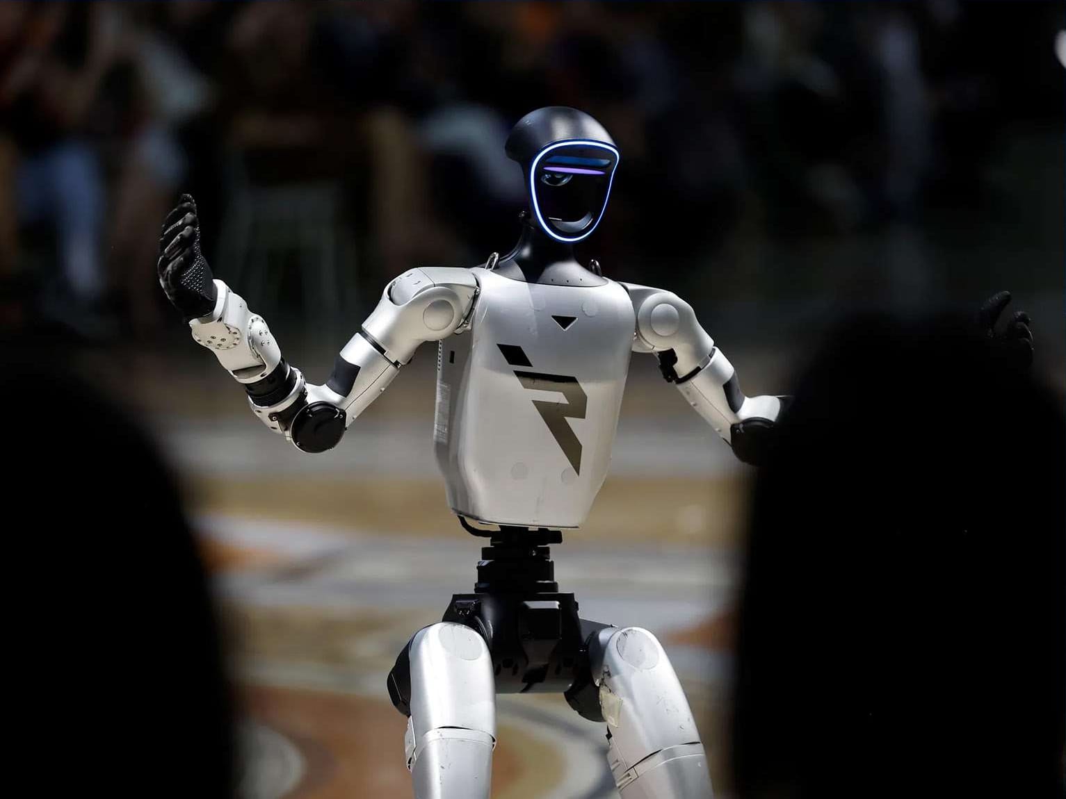 A white humanoid robot gesturing in front of a crowd
